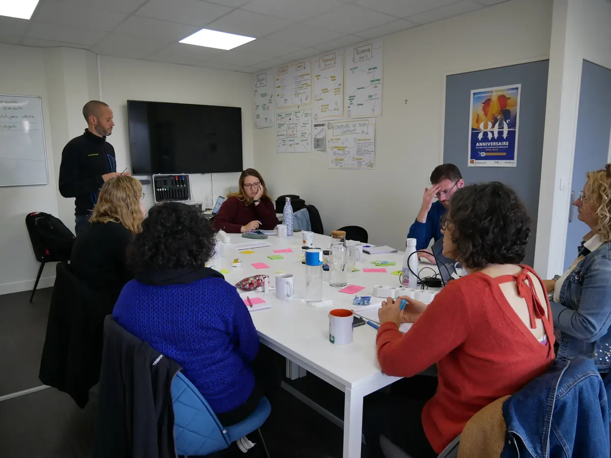 Groupe en formation à la coopération autour d'une table, productions affichées au mur